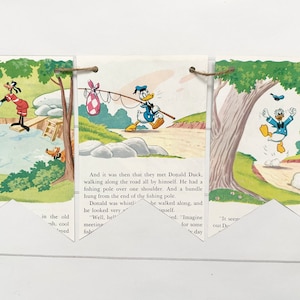 May include: A vintage children's book illustration featuring Donald Duck and Goofy. Donald Duck is walking along a path with a fishing pole and a bundle hanging from it. Goofy is swimming in a pond with other characters. The text reads "And it was then that they met Donald Duck, walking along the road all by himself. He had a fishing pole over one shoulder. And a bundle hung from the end of the fishing pole. Donald was whistling..."