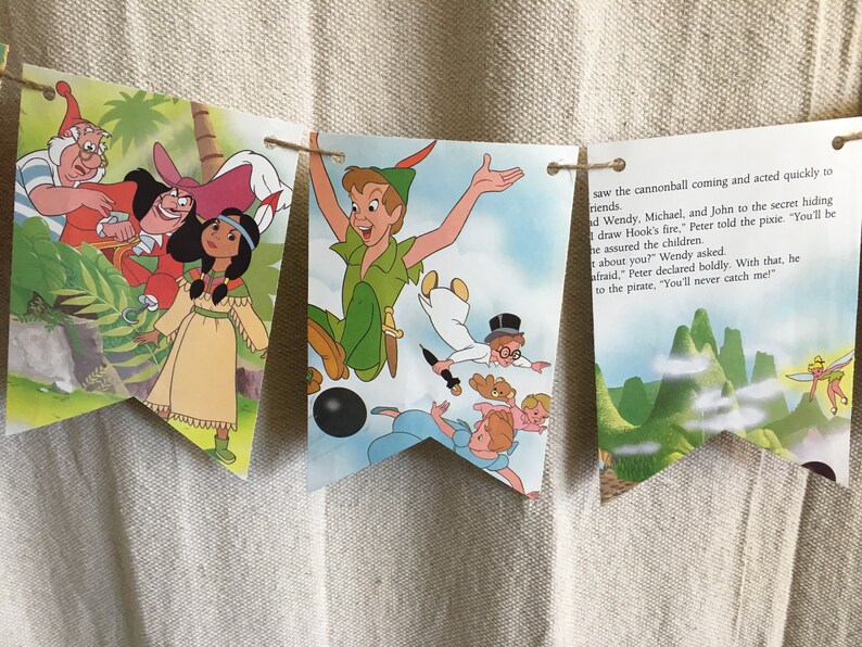 K&ouml;nnte beinhalten: Ein Peter-Pan-Banner mit Illustrationen von Peter Pan, Captain Hook und Tinkerbell. Das Banner ist aus Papier und hat eine Schnur, die durchl&auml;uft. Der Text auf dem Banner lautet: "saw the cannonball coming and acted quickly to friends. d Wendy, Michael, and John to the secret hiding draw Hook's fire," Peter told the pixie. "You'll be he assured the children about you?" Wendy asked. afraid," Peter declared boldly. With that, he to the pirate, "You'll never catch me!"