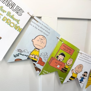 May include: A banner featuring Peanuts comic strip illustrations. The banner includes images of Charlie Brown, Lucy, and other characters, with text such as "Time for School" and "Psychiatric Help 5¢". The pennants are strung together with twine.