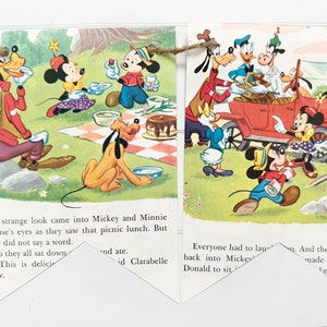May include: A vintage illustration of Mickey Mouse and friends enjoying a picnic. The characters are dressed in colorful clothing and are gathered around a checkered tablecloth. The illustration is printed on a banner with a string attached to each end.