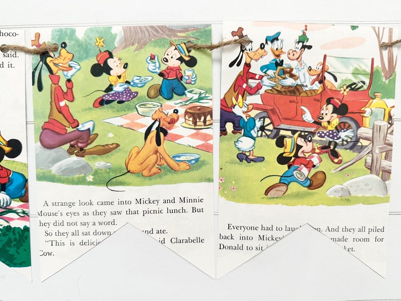 May include: A vintage illustration of Mickey Mouse and friends enjoying a picnic. The characters are dressed in colorful clothing and are gathered around a checkered tablecloth. The illustration is printed on a banner with a string attached to each end.