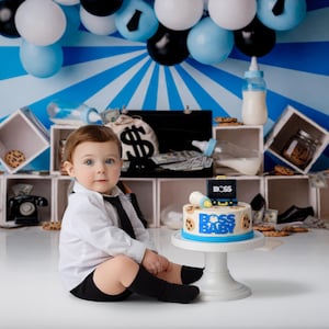 Op de afbeelding: Een baby in een wit overhemd en zwarte stropdas zit in de buurt van een taart met de tekst "BOSS BABY". De taart staat op een witte standaard. De achtergrond heeft blauwe en witte ballonnen en een blauwe achtergrond.