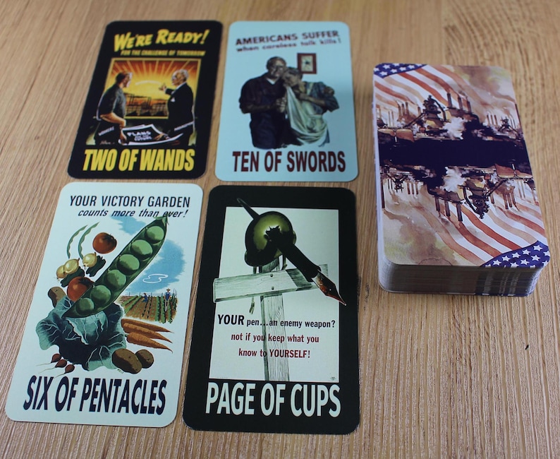 Puede incluir: Una baraja de cartas de juego de estilo vintage con ilustraciones patri&oacute;ticas y de propaganda. Las cartas presentan im&aacute;genes y texto, incluyendo "Two of Wands", "Ten of Swords", "Six of Pentacles" y "Page of Cups". La baraja est&aacute; apilada junto a cartas individuales.