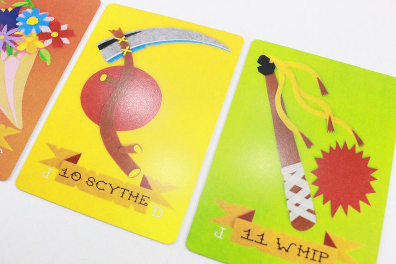 Puede incluir: Dos cartas de juego ilustradas con fondos amarillo y verde. La carta de la izquierda muestra una guada&ntilde;a roja y marr&oacute;n con el texto "10 SCYTHE". La carta de la derecha muestra un l&aacute;tigo marr&oacute;n con un borla amarillo y rojo y el texto "11 WHIP".