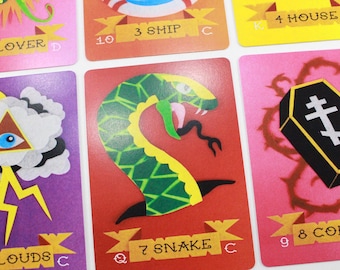 May include: A set of playing cards with colorful illustrations. The cards feature a clover, a ship, a house, clouds, a snake, and a coffin. The cards are numbered 2 through 9 and have a letter designation.