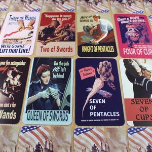 Puede incluir: Un conjunto de cartas de tarot de estilo vintage con temas patri&oacute;ticos. Cada carta presenta ilustraciones y texto &uacute;nicos, como "Three of Wands", "Two of Swords" y "Four of Cups". Las cartas est&aacute;n dispuestas sobre una superficie con un dise&ntilde;o de bandera estadounidense.