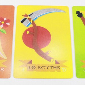 Puede incluir: Tres cartas ilustradas con fondo rojo, amarillo y verde. Las cartas est&aacute;n numeradas del 9 al 11. Las cartas representan un ramo de flores, una guada&ntilde;a y un l&aacute;tigo.