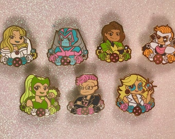 May include: Set of seven enamel pins featuring characters from the X-Men comics. Each pin is gold-toned and features a different character with a floral design around them. The characters include: Jean Grey, Beast, Gambit, Rogue, Polaris, Nightcrawler, and Psylocke.