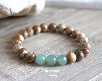 Puede incluir: Un brazalete de cuentas marrones y verdes con un acento de piedra verde claro. El brazalete está hecho de piedras naturales y es un gran accesorio para cualquier ocasión.