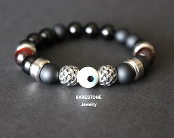 May include: Black and silver beaded bracelet with a white evil eye charm. The bracelet features a woven design on the silver beads. BARESTONE Jewelry.