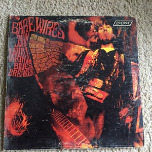 May include: A vintage vinyl record cover featuring a close-up of John Mayall, the lead singer of John Mayall's Bluesbreakers, with a red, orange, and yellow background. The album title "Bare Wires" is written in a large, stylized font. The record label is London Records.