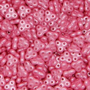 May include: A close-up of a pile of pink, three-holed, plastic beads. The beads are shaped like a butterfly.