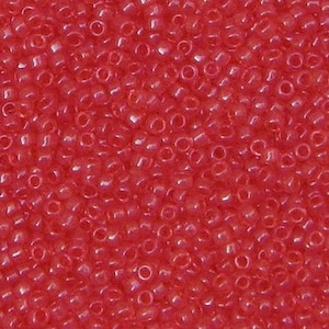 Puede incluir: Vista de cerca de una gran cantidad de pequeñas cuentas de semillas redondas de color rojo. Las cuentas son opacas y tienen un ligero brillo.