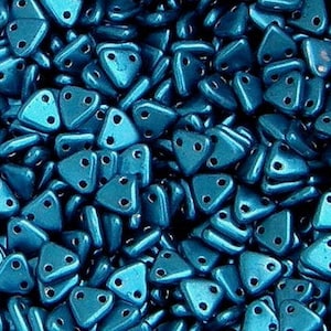 May include: A close-up of a pile of teal blue triangle-shaped beads with two holes in each bead.