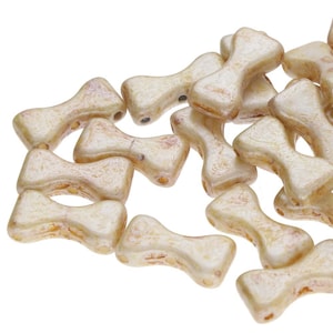 Puede incluir: Un montón de cuentas de vidrio de color blanco roto en forma de lazo con un brillo sutil. Las cuentas tienen una superficie ligeramente texturizada.