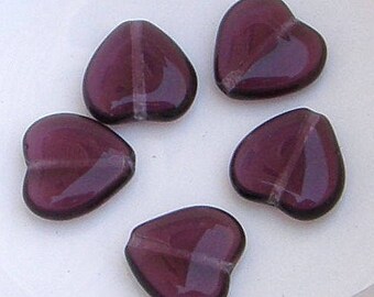 May include: Five purple glass heart-shaped beads. The beads are translucent and have a slight shimmer.