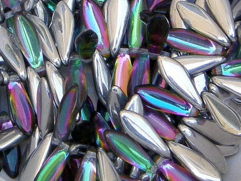 May include: A close-up of iridescent glass beads in a teardrop shape. The beads have a silver, green, purple, and blue iridescent finish.
