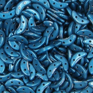 May include: A large quantity of teal blue crescent-shaped beads with three holes each. The beads have a metallic sheen.