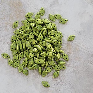 May include: A large pile of small, green, diamond-shaped beads with two holes in each bead.