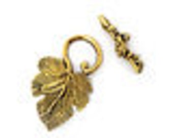 May include: Gold-toned metal toggle clasp with a leaf design. The clasp features a detailed leaf pendant and a bar with decorative accents. The leaf pendant is approximately 1 inch in length. The clasp is designed for jewelry making and crafts.