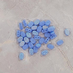 May include: A group of light blue oval-shaped glass beads with an iridescent finish.
