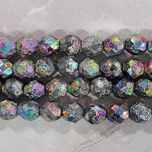 May include: A strand of iridescent black glass beads with a faceted, textured finish. The beads have a rainbow sheen.