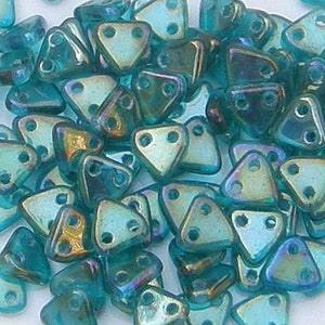 May include: A pile of teal iridescent triangle shaped beads with two holes each. The beads are made of glass and have a metallic sheen.