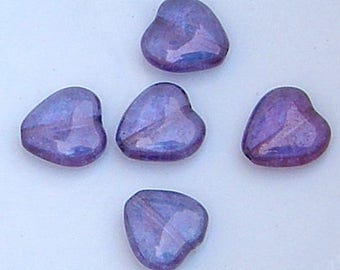 May include: Five heart-shaped beads in shades of purple and blue. The beads have a glossy, iridescent finish, reflecting light. The beads are arranged on a white surface. These beads are suitable for jewelry making and crafts.