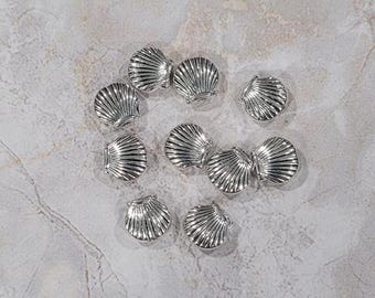 May include: A collection of silver-toned seashell charms. The charms are all in the shape of a seashell and have a smooth, shiny finish.