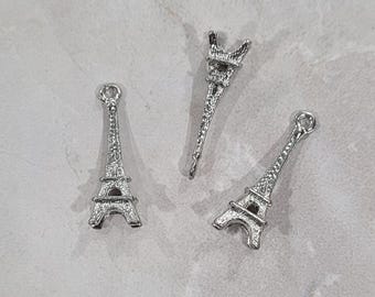 May include: Three silver Eiffel Tower charms. The charms are detailed and have a textured surface.