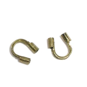 May include: Two gold-toned metal crimp end caps for jewelry making. The caps are shaped like a U with a small cylinder on each end.
