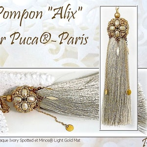 以下が含まれることがあります： 「Pompon "Alix" par Puca®-Paris」と「Puca®」のテキストが書かれた、金とアイボリーのビーズのタッセルペンダントです。