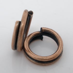 May include: Two copper jump rings, one is open and the other is closed. The rings are about 1/2 inch in diameter.