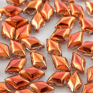 May include: A scattering of small, iridescent orange diamond-shaped glass beads. The beads have a reflective, almost metallic finish.