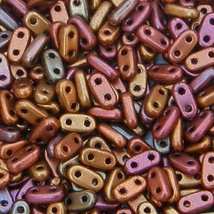 May include: A close-up image of a large quantity of small, oval-shaped beads. The beads are a mix of metallic gold, copper, and bronze colors. The beads have two holes on each side.