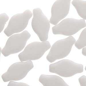 May include: A group of white, opaque, glass beads in a teardrop shape with rounded edges. The beads are scattered on a white background.