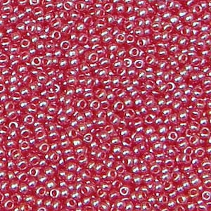 May include: A close-up image of a large quantity of small, round, red seed beads. The beads have a slight iridescent sheen.
