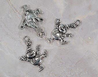 May include: Three silver charm pendants featuring a snowman design. The snowman charms are wearing hats and scarves and are in different poses. The charms are perfect for adding a festive touch to jewelry or crafts.