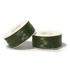 May include: Two spools of olive green thread are displayed against a white background. The thread is tightly wound around white cardboard spools. The spools are positioned at different angles, showcasing the thread's color and texture. The thread appears to be a fine, durable material.