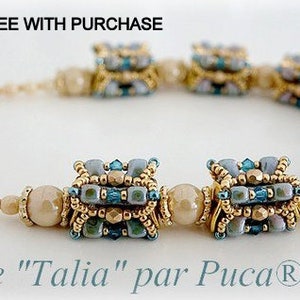 Op de afbeelding: Een beige en blauwe kralenketting met gouden accenten. De ketting heeft een herhalend patroon van vierkante kralen. De tekst "Perle "Talia" par Puca®-Paris" is zichtbaar onderaan de afbeelding.