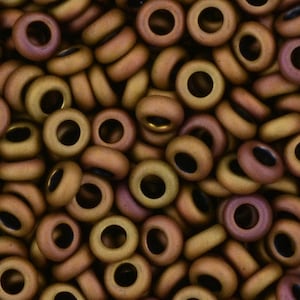 May include: A close-up image of a pile of small, round, brown and gold beads with a hole in the center. The beads have a matte finish.