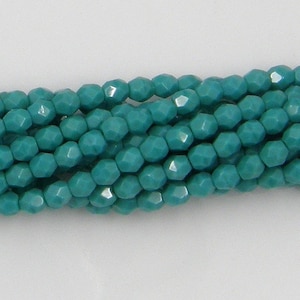 May include: Close-up of strands of turquoise beads. The beads are faceted, catching the light. The teal beads are strung together, creating a textured effect. These beads are suitable for jewellery making and craft projects. Each bead is approximately 0.4 cm in diameter.