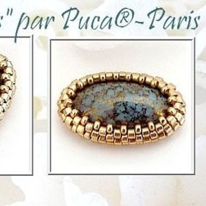 以下が含まれることがあります： 中央に灰色の石が埋め込まれた、金色の楕円形のビーズ模様のクローズアップ。ビーズ模様は「Serti Athos」と呼ばれ、Puc@-Parisによって作られています。