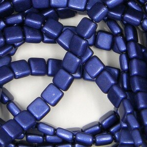 May include: A strand of dark blue square glass beads. The beads have a matte finish and are strung on a clear thread.