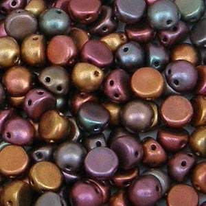 May include: A collection of small, round, two-hole beads in a metallic finish. The beads feature a palette of bronze, copper, plum, and dark green tones with a smooth, slightly iridescent surface texture, arranged in a dense, overlapping pile.