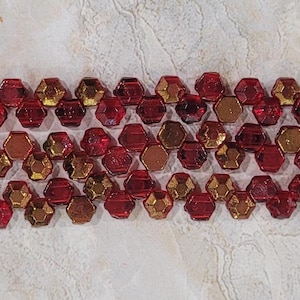 May include: A strand of red and gold hexagonal glass beads. The beads have a faceted, iridescent finish.
