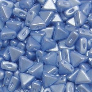 May include: A close-up of a pile of light blue triangle-shaped beads. The beads have a smooth, shiny finish.