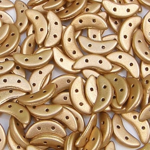 May include: A collection of crescent moon-shaped beads in a matte gold finish. Each bead features two small holes positioned along the center of the curved body, allowing for versatile threading and connection in various jewelry making projects.