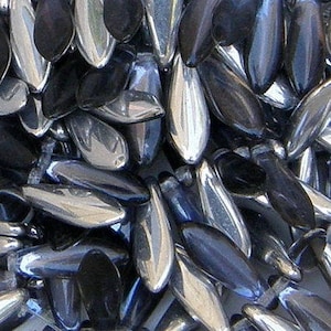 May include: A close-up of a pile of silver and black glass beads. The beads are shaped like teardrops and have a shiny, iridescent finish.