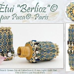 May include: A close-up of a small, beaded, gold and blue bottle stopper with a screw-on top. The bottle stopper is labeled "Étui "Berlioz"© par Puca®-Paris".